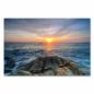 Preview: Die untergehende Sonne taucht das Meer und Felsen am Strand in ein goldenes Licht.