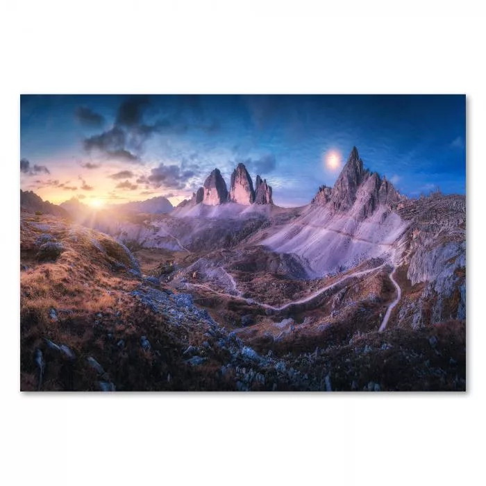 Schroffe Berggipfel ragen in den Abendhimmel. Ein Wanderweg schlängelt sich durch die karge Landschaft. Die untergehende Sonne taucht die Szenerie in ein warmes Licht.