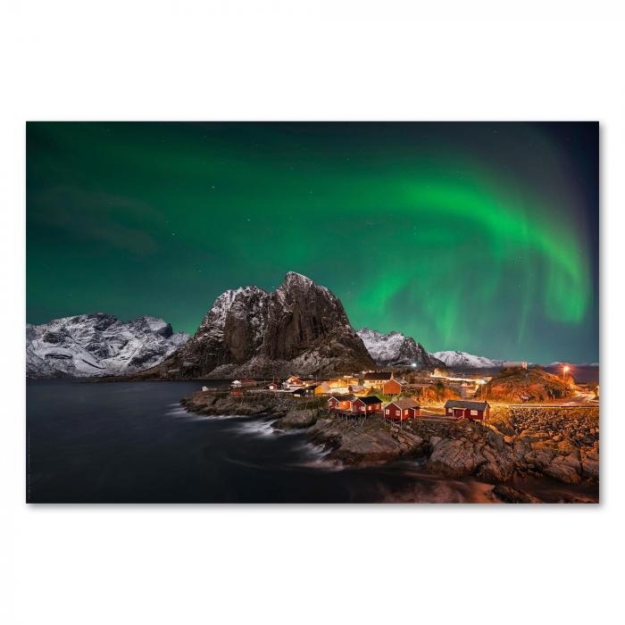 Magische Nordlichter tanzen über verschneitem Fischerdorf in Norwegen, erleuchtete Häuser spiegeln sich im Wasser.