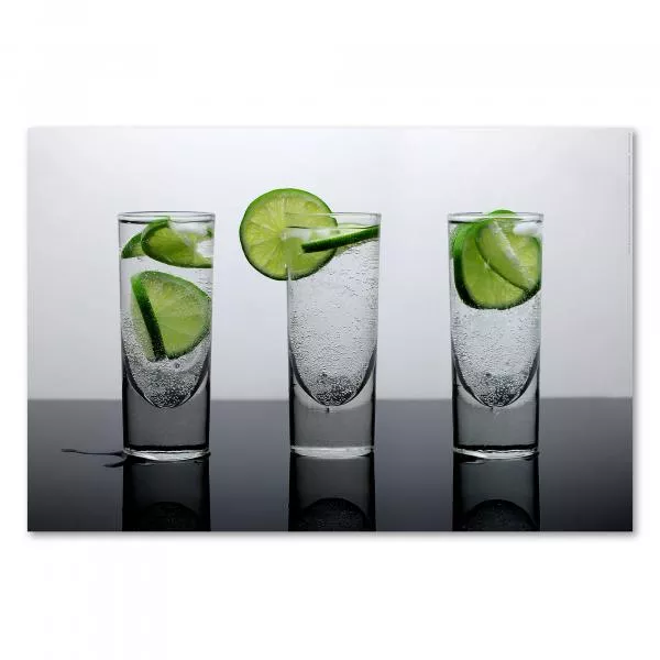 Drei Gläser mit prickelnder Limonade und frischen Limettenscheiben vor einem grauen Hintergrund. Drei Gläser mit prickelnder Limonade und frischen Limettenscheiben vor einem grauen Hintergrund.