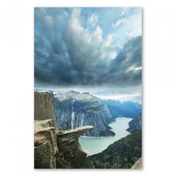 Eine Person steht mutig an der Trolltunga in Norwegen und genießt den atemberaubenden Fjordblick. Eine Person steht mutig an der Trolltunga in Norwegen und genießt den atemberaubenden Fjordblick.