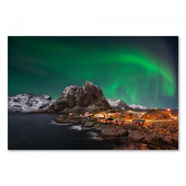 Magische Nordlichter tanzen über verschneitem Fischerdorf in Norwegen, erleuchtete Häuser spiegeln sich im Wasser.