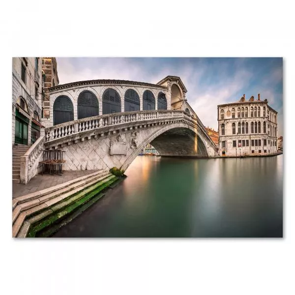 Rialtobrücke in Venedig, Sonnenaufgang, warme Farben spiegeln sich im Kanal. Rialtobrücke in Venedig, Sonnenaufgang, warme Farben spiegeln sich im Kanal.