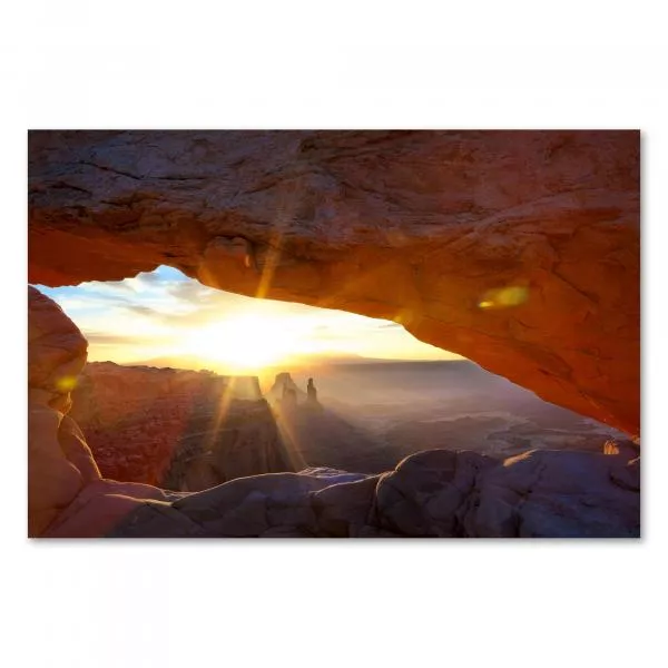 Die aufgehende Sonne taucht einen weiten Canyon in goldenes Licht, Blick durch einen natürlichen Felsbogen. Die aufgehende Sonne taucht einen weiten Canyon in goldenes Licht, Blick durch einen natürlichen Felsbogen.