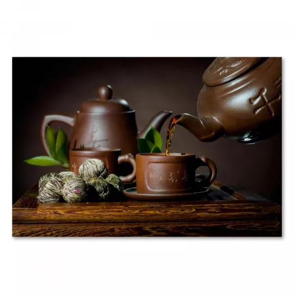 Teekanne aus Ton gießt heißen Tee in Tasse, umgeben von Teeblättern & -blüten. Teekanne aus Ton gießt heißen Tee in Tasse, umgeben von Teeblättern & -blüten.