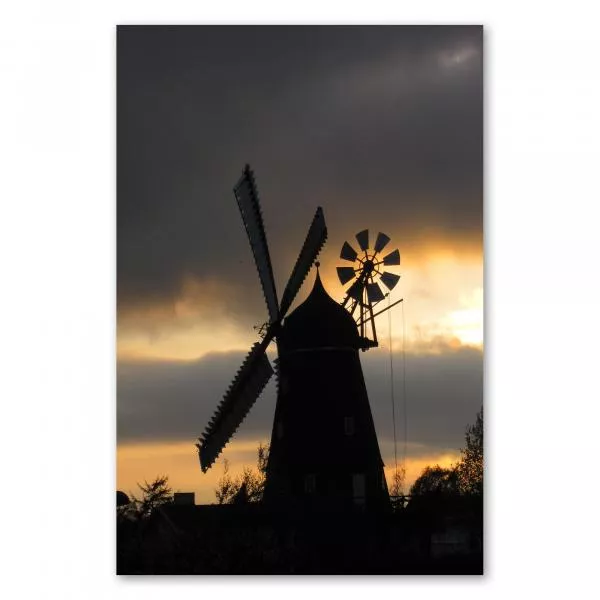 Silhouette einer Windmühle vor dramatischem Abendhimmel mit rot-orangen Wolken und untergehender Sonne. Silhouette einer Windmühle vor dramatischem Abendhimmel mit rot-orangen Wolken und untergehender Sonne.